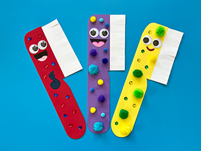 Three colourful paper toothbrushes on a blue background