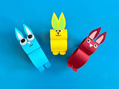 Three bunnies made out of coloured rolls of construction paper.